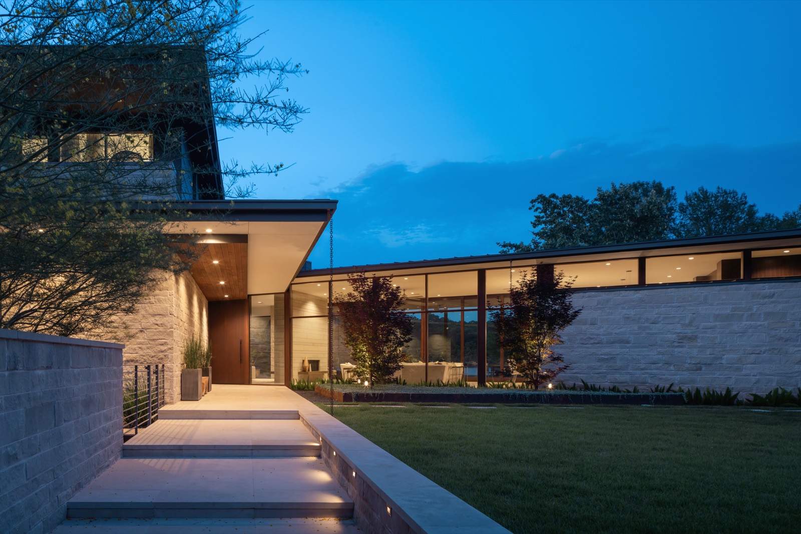 A modern Above residence in Austin at dusk, glass walls glowing
